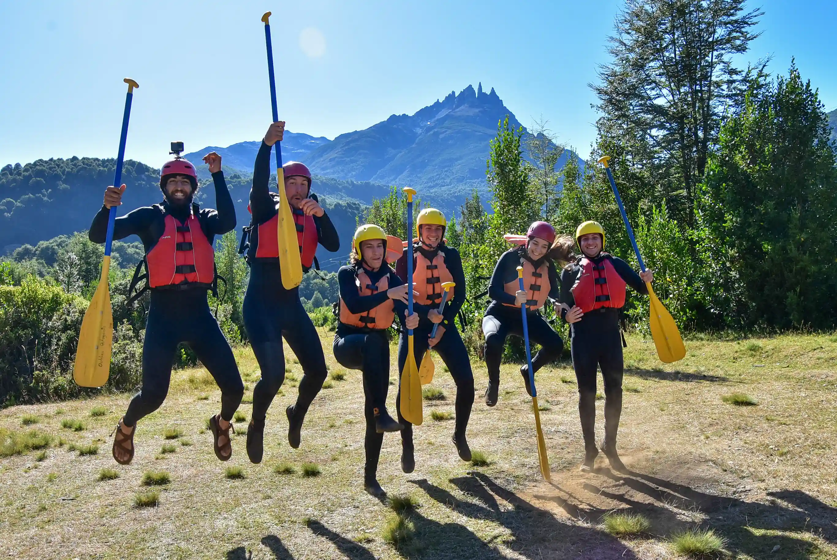 Grupo de rafting saltando con remos después del descenso
